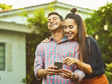 couple laughing while looking at a phone