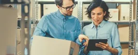 co workers looking at a tablet while holding a box