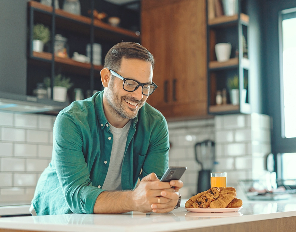 A man in a green shirt looking at his phone.