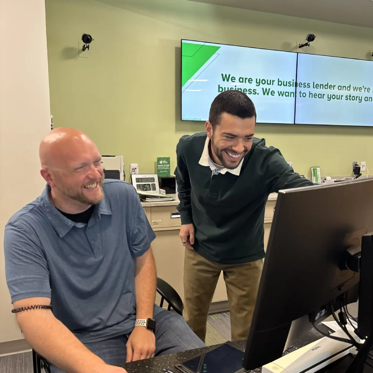 Darian Miles y un miembro del equipo riendo y mirando la pantalla de un ordenador
