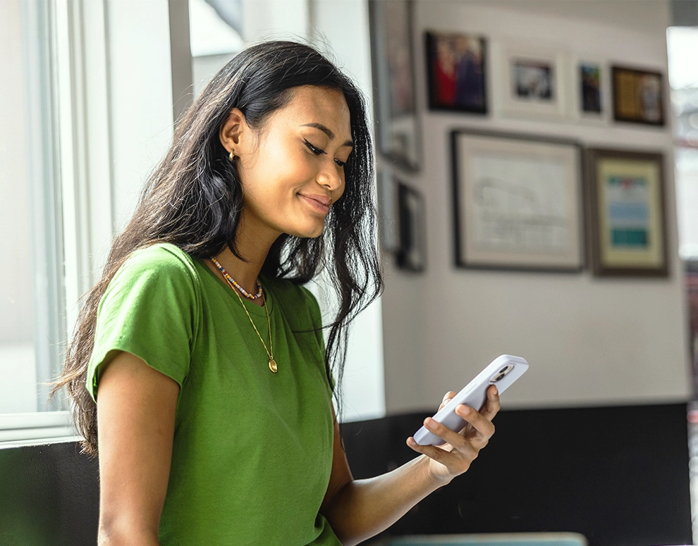 A woman wearing a green shirt looking at her phone.