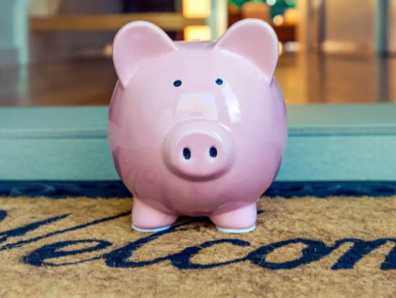 A piggy bank on the welcome mat of a home.