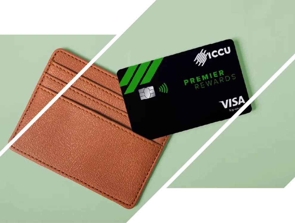 An ICCU Premier Rewards credit card beside a brown wallet on a green background.