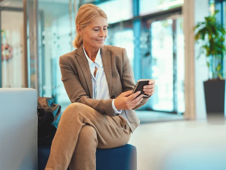 Business professional using smartphone in modern indoor setting.