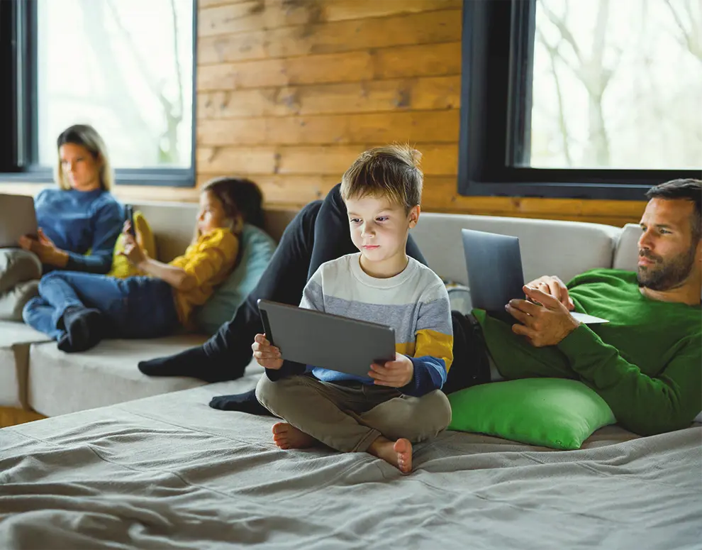 Family using digital devices together in a cozy living room, highlighting safe technology use and cybersecurity awareness at home.