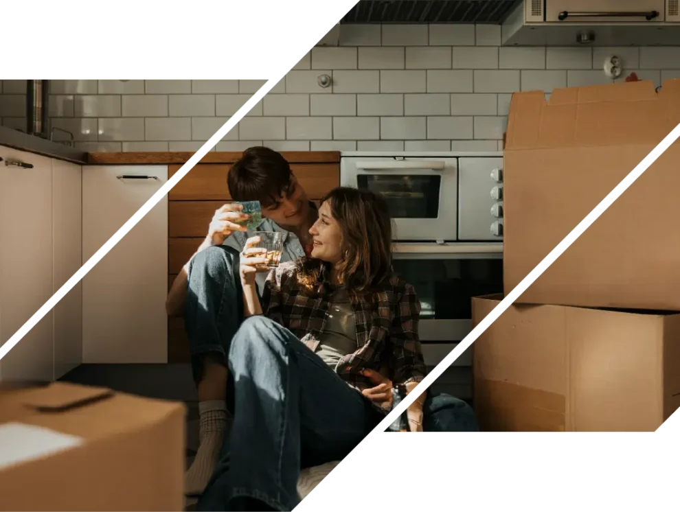 A man and woman sitting in a kitchen with moving boxes.