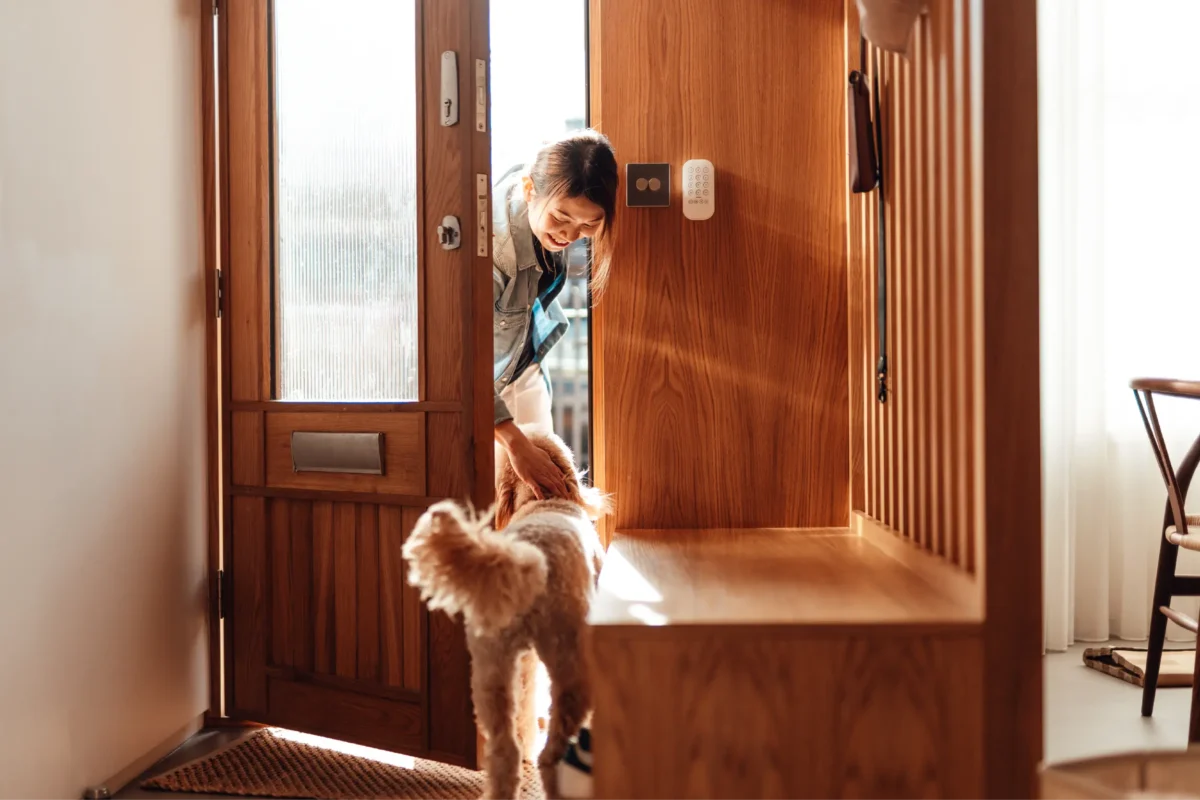 A woman walks into her new home and greets her dog in the doorway.