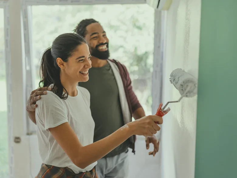 A happy couple painting green walls together during a home improvement project.