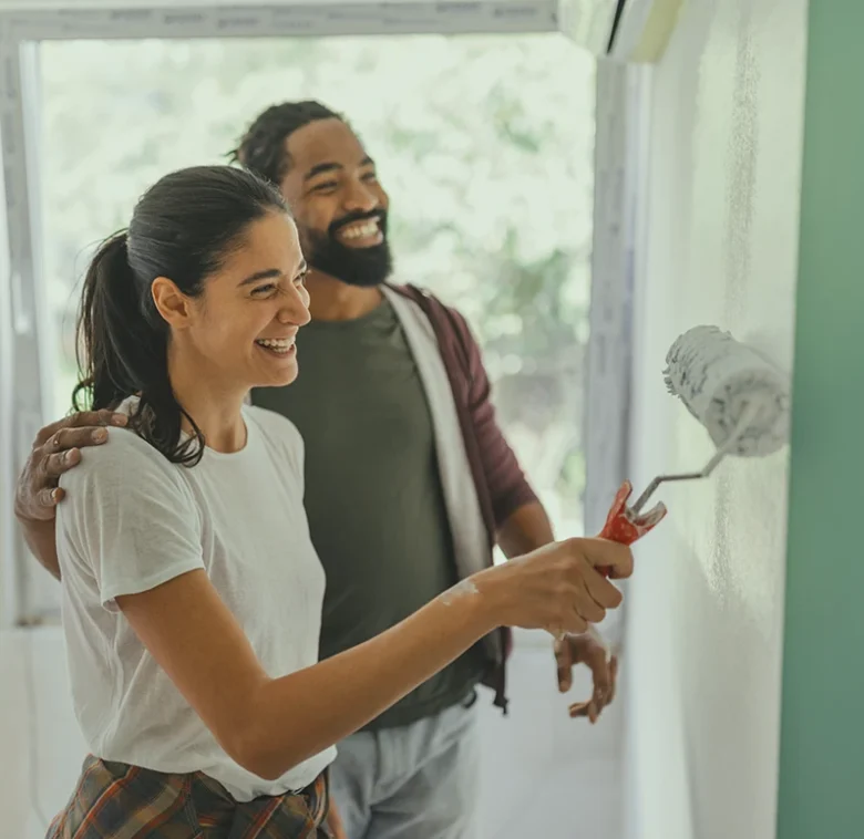 A happy couple painting green walls together during a home improvement project.