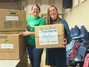 ICCU Volunteers holding donation boxes for Project Warm-Up at a community collection event