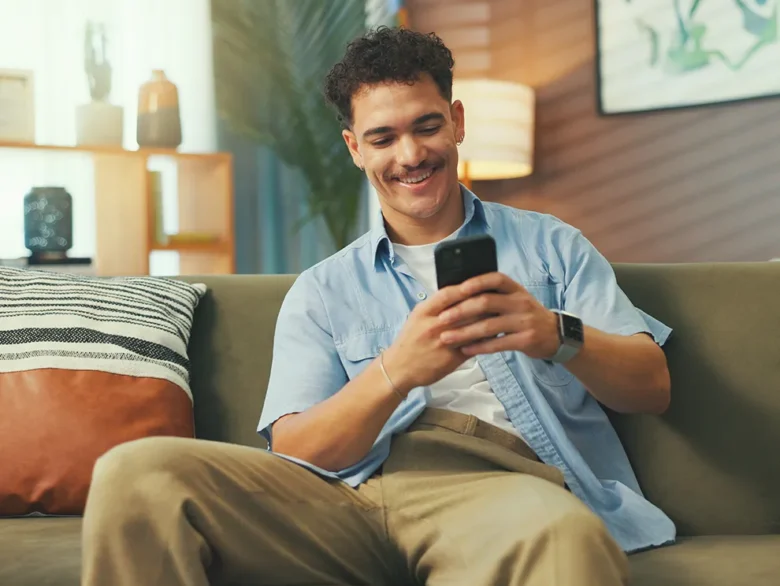 Individual using a smartphone at home, symbolizing eBranch card controls and real time account management