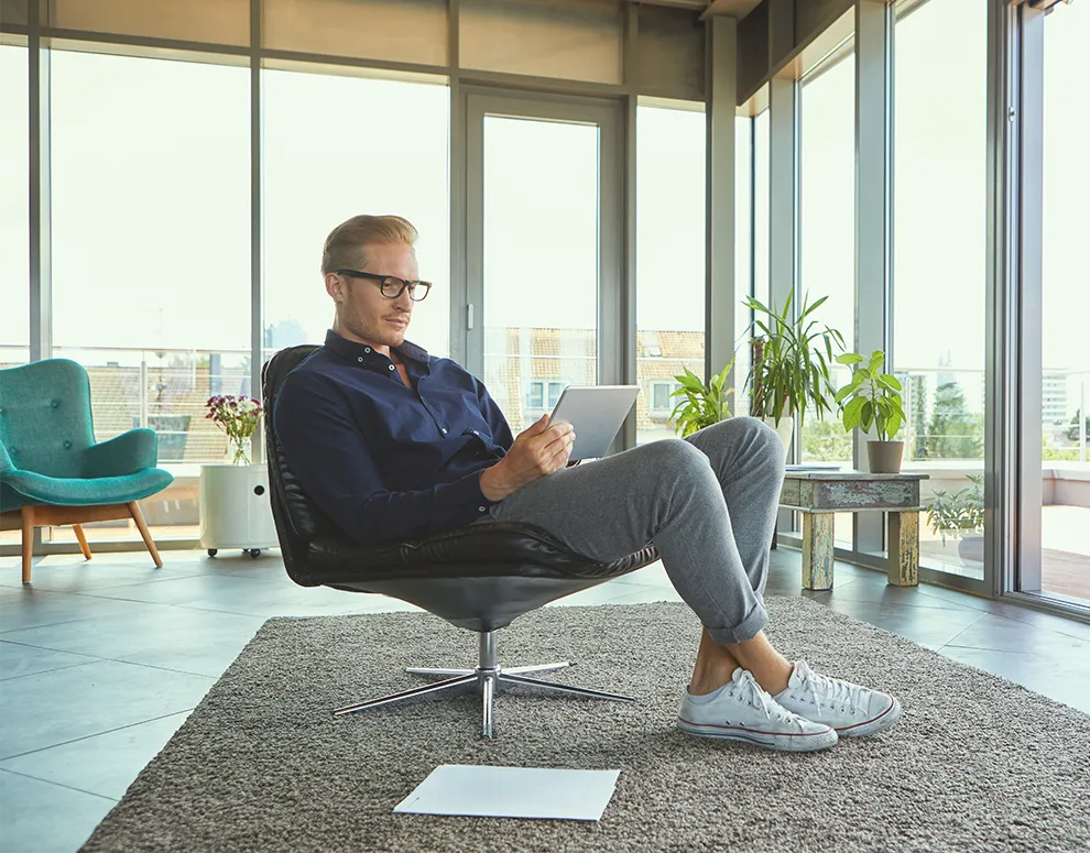 Person seated in a modern living space using a tablet to review information