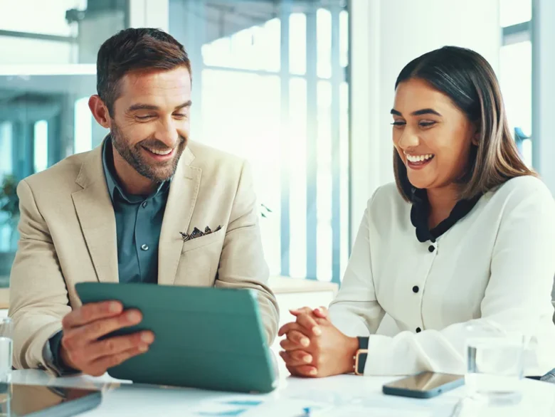 Financial planning conversation with an advisor and client reviewing details on a tablet in a professional office