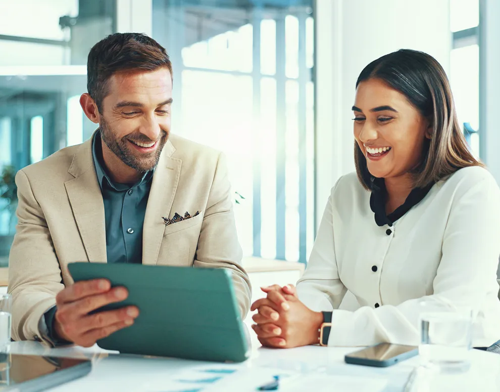 Financial planning conversation with an advisor and client reviewing details on a tablet in a professional office