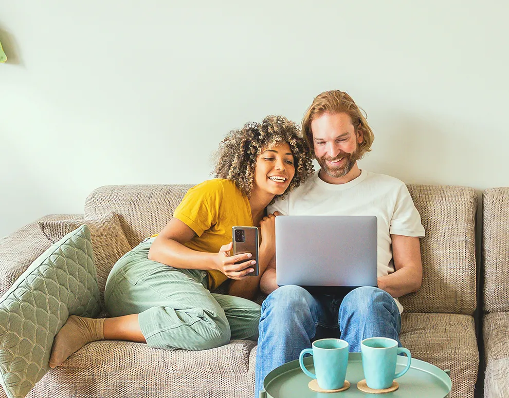Pareja utilizando un ordenador portátil en casa, simbolizando el acceso a eBranch y la facilidad del apoyo financiero digital