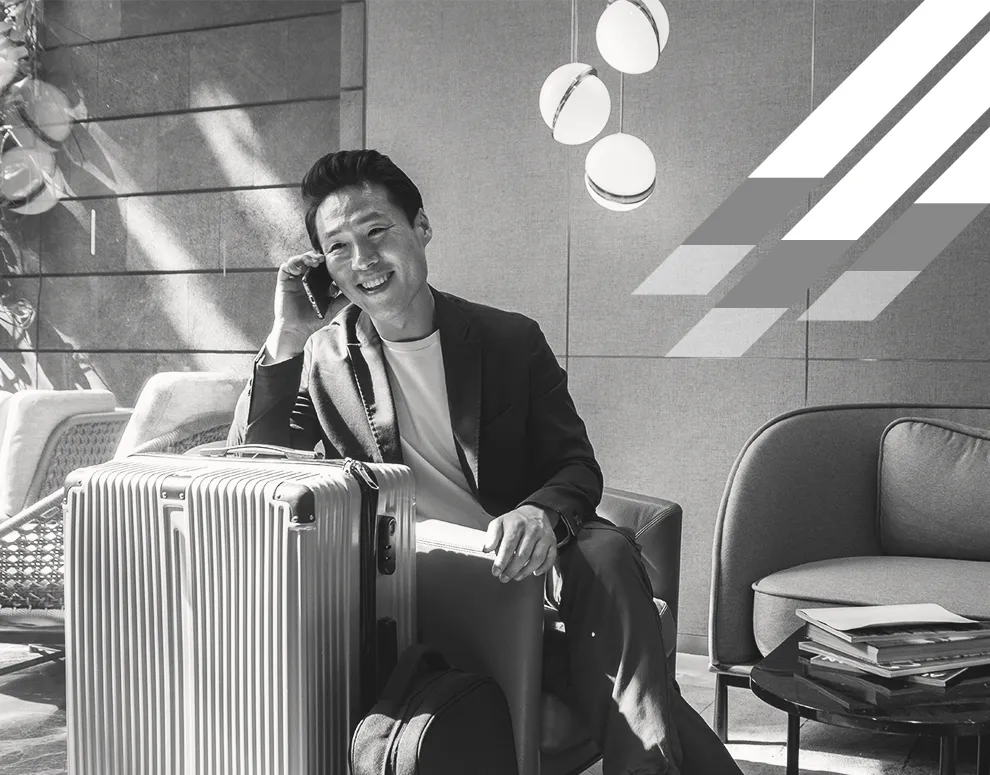 Individual sitting with luggage and talking on a phone in a modern interior, symbolizing financial mobility and ongoing guidance