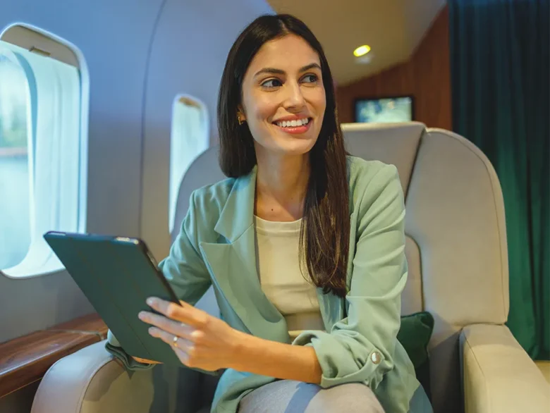 Individual using a tablet inside a private aircraft, symbolizing financial confidence and long term planning