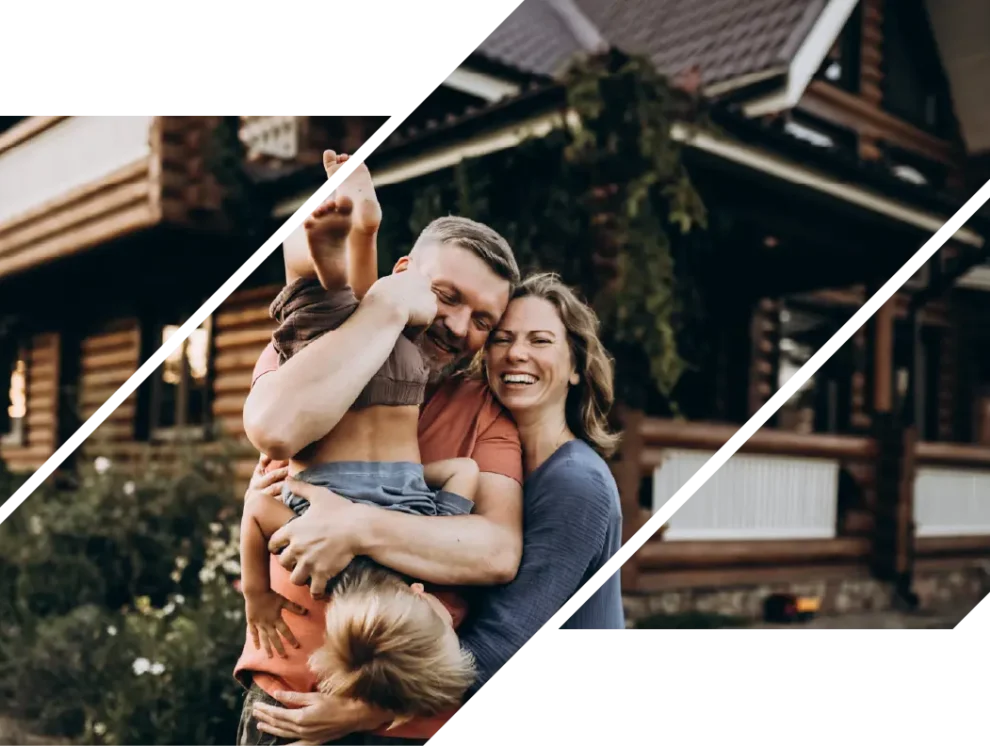 A smiling couple plays with their son in front of their new house.