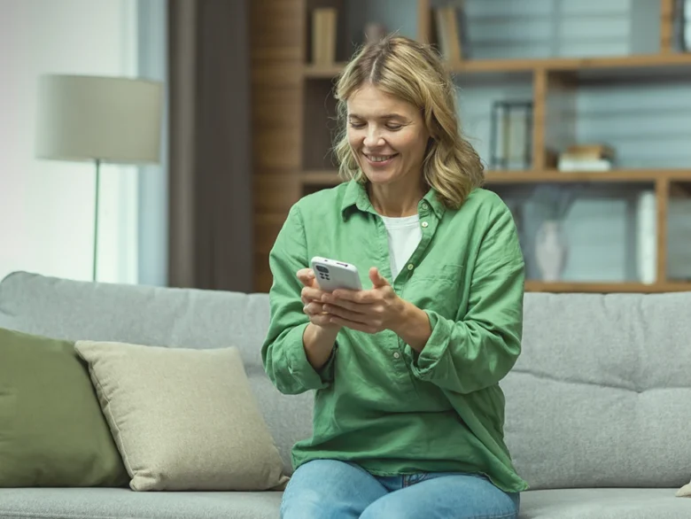 Woman in green top sitting on a sofa, looking at her phone