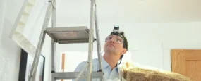 Homeowner adding insulation in an attic to increase energy efficiency and lower energy costs