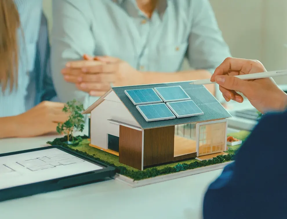 Person pointing at solar panels on a model home while discussing energy-efficient upgrades and green financing