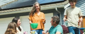 Residential home with rooftop solar panels during an outdoor gathering, representing solar loan benefits and energy savings