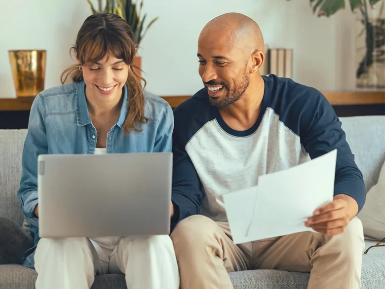 Couple reviewing bank statements online with laptop and documents, accessing eStatements through secure eBranch account