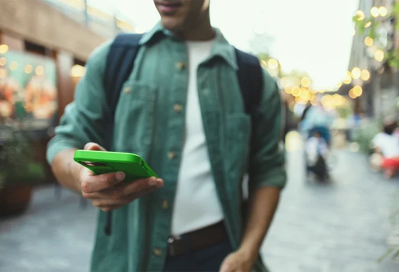 Person using a smartphone outdoors while accessing online banking tools for ICCU High-Yield Online Savings.