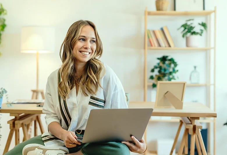 A woman smiling while holding her laptop.