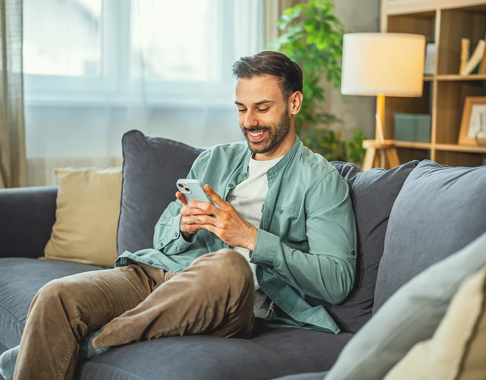 Person using a smartphone at home to manage savings and financial goals online.